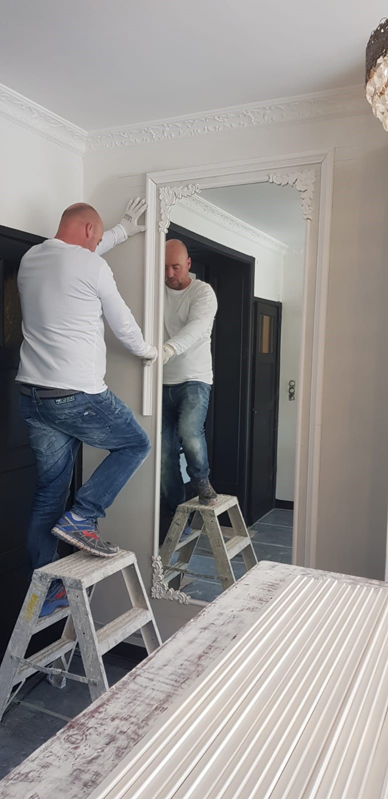 Stukadoor René Egas brengt lijstwerk aan op de muur. 